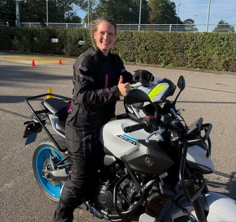 Leerling in motorkleding steekt haar duim op op de Yamaha MT-07 op het oefenterrein
